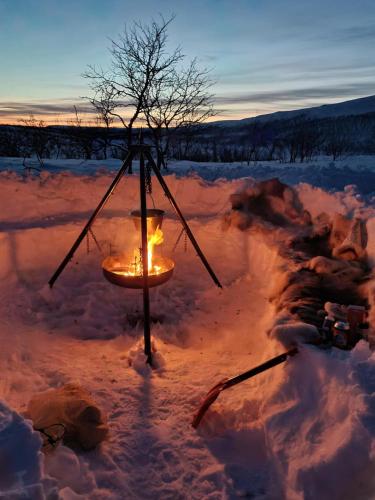 un candelabro en la nieve al atardecer en Finnmark Glamping, en Alta