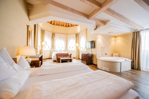 a large room with two beds and a bath tub at Hotel Fameli in Valdaora