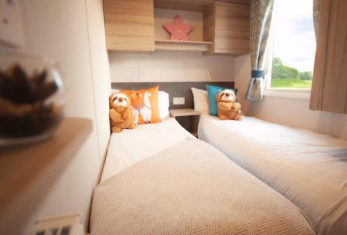 dos ositos de peluche sentados en dos camas en una habitación en Sandylands Holiday Home, en Stevenston