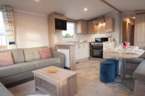 a kitchen and living room with a couch and a table at Sandylands Holiday Home in Stevenston
