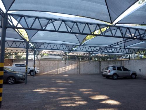 een parkeerplaats met auto's geparkeerd onder een metalen constructie bij Hotel Cristal in Mendoza