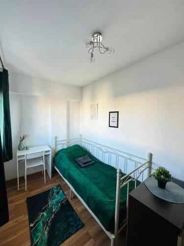a bedroom with a bed with a green blanket at City View Rooms in Warsaw