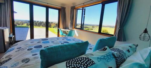 a bedroom with a bed and windows with a view at Hill Top Retreat in Lower Dashwood