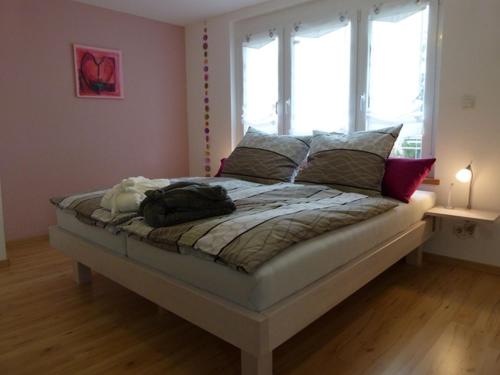 ein großes Bett in einem Zimmer mit zwei Fenstern in der Unterkunft Elisabeth - herrliche Seesicht in Überlingen