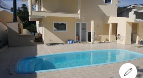 a swimming pool in front of a house at Casa completa com piscina no Paraíso do Brasil in Governador Celso Ramos