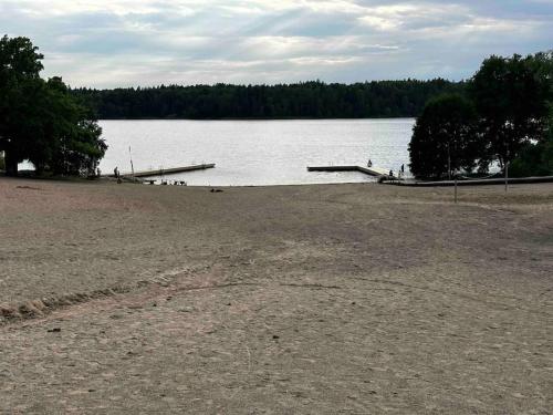 an empty beach with a dock on a lake at Villa Trollbäcken med bastu, värmegolv, öppen spis in Tyresö