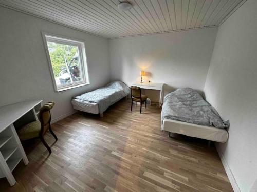a room with two beds and a desk and a window at Villa Trollbäcken med bastu, värmegolv, öppen spis in Tyresö