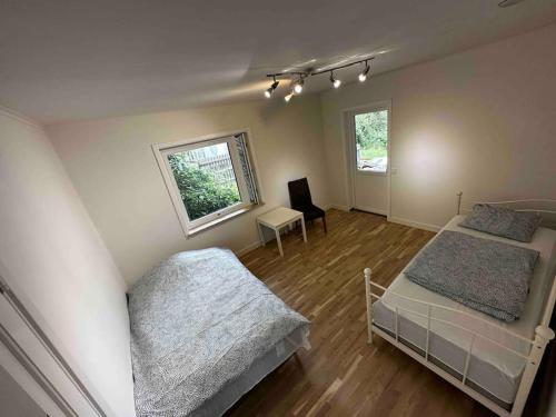 a bedroom with two beds and a desk and a window at Villa Trollbäcken med bastu, värmegolv, öppen spis in Tyresö