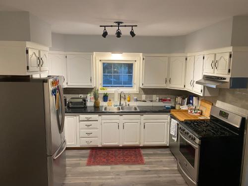 uma cozinha com armários brancos e um frigorífico preto em Modern Beach House long stay discounts em Sarnia
