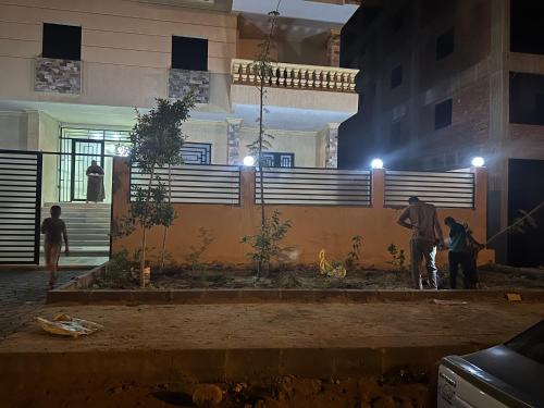 un grupo de personas de pie fuera de un edificio por la noche en مدينة الشروق, en Madīnat ash Shurūq