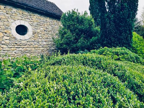 a brick building with a round window and bushes at 1700's Country House with large Private Pool & Gardens in Villeneuve-dʼAveyron