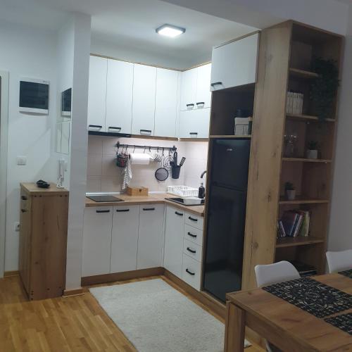 a kitchen with white cabinets and a black refrigerator at Apartman Dunjic in Vrnjačka Banja