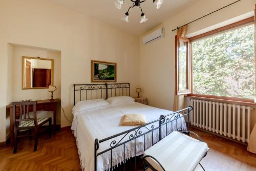 a bedroom with a bed and a window and a chair at Holiday House Borgo Badia in Castiglione del Lago