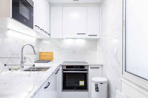 une cuisine blanche avec un évier et une cuisinière dans l'établissement Paris coeur, un superbe appartement de 40 m2., à Paris