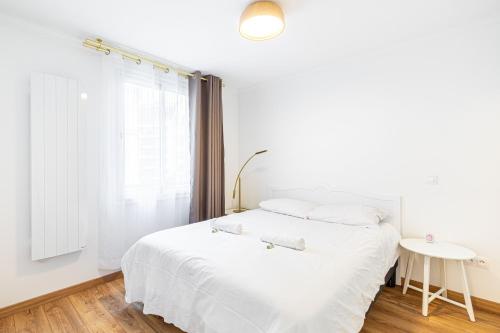une chambre blanche avec un lit et une table dans l'établissement Paris coeur, un superbe appartement de 40 m2., à Paris