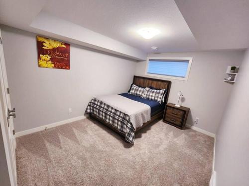 a small bedroom with a bed and a window at Deluxe 2 bedroom suite with*Netflix/Cable/Prime in Edmonton