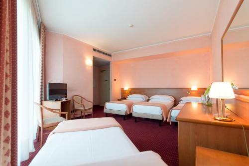 a room with a row of beds and a television at Airport Hotel Bergamo in Bagnatica