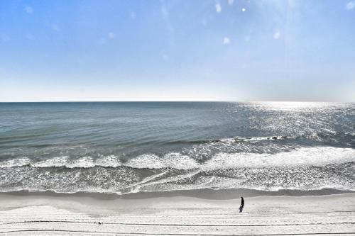 a person standing on the beach near the ocean at 0611 Waters Edge Resort condo in Myrtle Beach