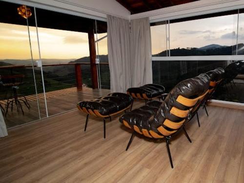 um quarto com 3 cadeiras de couro numa varanda em Pousada Colina das Andorinhas em Gonçalves