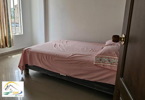 a bedroom with a bed with a pink blanket at Hostal Sinaí in Mocoa