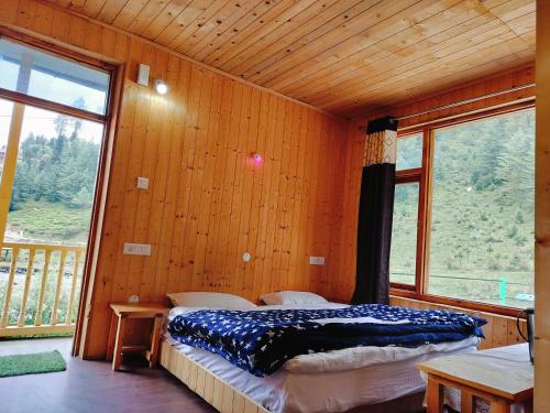 a bedroom with a bed and a large window at Shiva Valley Riverside Home Stay in Jibhi