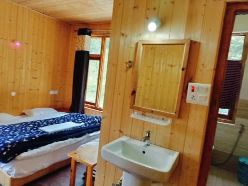 a bathroom with a sink and a bed in a room at Shiva Valley Riverside Home Stay in Jibhi