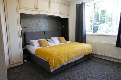 Huge 9 Bed Property Sleeps 17, Near NEC, City Centre, HS2 في برمنغهام: غرفة نوم بسرير كبير مع بطانية صفراء