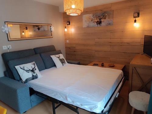 une chambre avec un grand lit et un canapé bleu dans l'établissement Appartement les orres 1800 pied des pistes, aux Orres