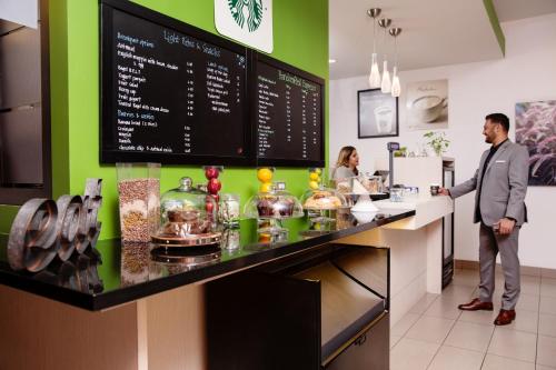 a man standing at a counter in a restaurant at Delta Hotels by Marriott Edmonton South Conference Centre in Edmonton