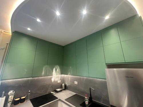 een keuken met groene muren en een wastafel bij T.A.O APARTMENT in Tirana