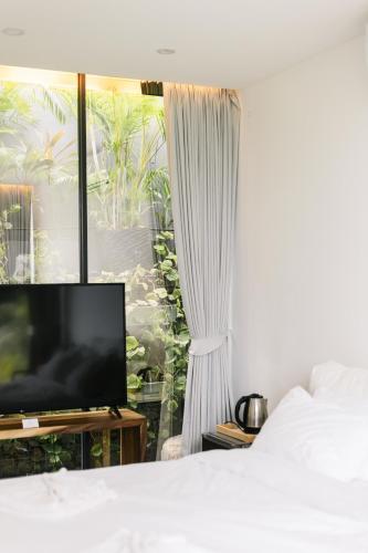 a bedroom with a bed and a tv and a window at Villa Obsidian, sea view and walk to Choeng Mon beach in Choeng Mon Beach