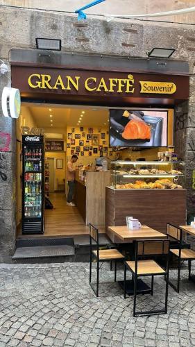 ein Laden mit Tischen und Stühlen vor einer Bäckerei in der Unterkunft Sciuscià beb spaccanapoli in Neapel