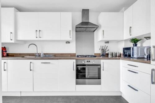 a white kitchen with white cabinets and a sink at City Centre 3 Bedroom House Sleep upto 9 Guests with Garden and Parking in Birmingham