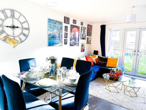 a living room with a table and a clock on the wall at City Centre 3 Bedroom House Sleep upto 9 Guests with Garden and Parking in Birmingham