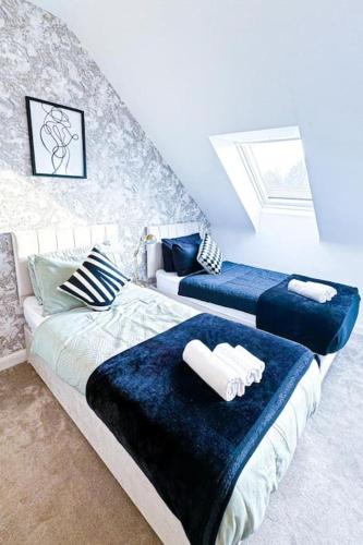 a bedroom with two beds with blue sheets and a window at City Centre 3 Bedroom House Sleep upto 9 Guests with Garden and Parking in Birmingham