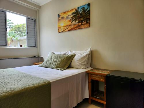 een kleine slaapkamer met een bed en een televisie bij Flats Enseada Delphin in Guarujá