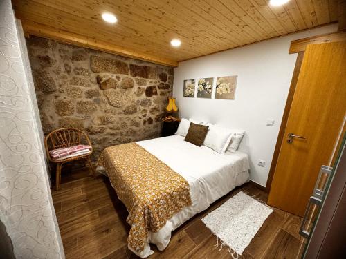1 dormitorio con cama y pared de piedra en Casa da Vila - Apartamento rés chão, en Alpedrinha