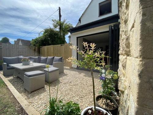 a patio with a couch and a table in a backyard at Large Stylish Luxury Cotswold Cottage - ideal for families, w/ EV charging in Andoversford