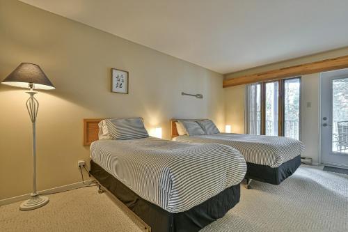 een slaapkamer met 2 bedden, een lamp en een raam bij Semi Suit Sunshine in Mont-Tremblant