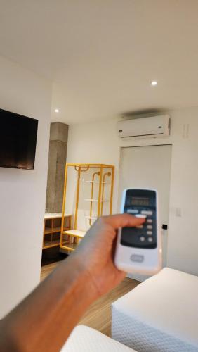 a persons hand holding a remote control in a room at BOURBON HOSTAL in Juayúa