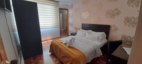 a bedroom with a bed with white sheets and a window at Casa Coliving 121 in Bogotá