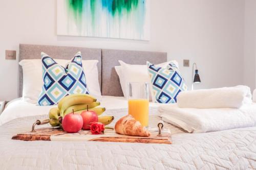 a tray of fruit on a bed with a glass of orange juice at BRAND NEW Apartments with FREE Parking and WIFI! in Staines