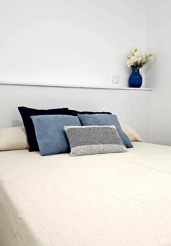 - un lit blanc avec des oreillers bleus et un vase au-dessus dans l'établissement La Caseta Blava 2, à Benidorm