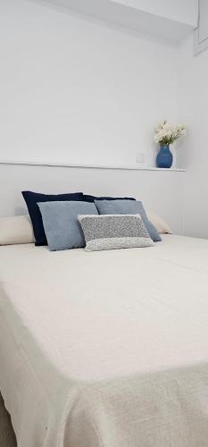 - un lit blanc avec des oreillers bleus dans l'établissement La Caseta Blava 2, à Benidorm