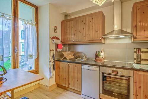 une cuisine avec des armoires en bois et un four à plaques de cuisson dans l'établissement Appartement Yodel - Welkeys, à Saint-Gervais-les-Bains