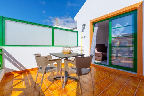 a dining room with a table and chairs on a balcony at Dunas of Love in Caleta De Fuste
