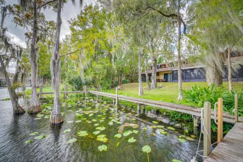 a pond with water lilies and trees and a house at Waterfront Dunnellon Retreat with River Access! in Dunnellon