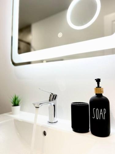 a black bottle of soap sitting on a bathroom sink at Extravagant 3 Bedroom Near art Museum in Philadelphia
