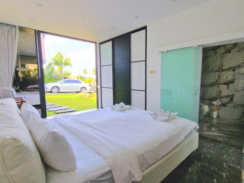 a bedroom with a white bed with a large window at Villa Obsidian, sea view and walk to Choeng Mon beach in Choeng Mon Beach