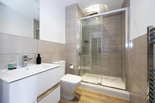 a bathroom with a shower and a toilet and a sink at Bright Stylish Studio Apartment in Old Trafford in Manchester
